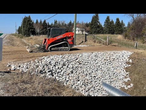 Видео: УСТАНОВКА ВОДОПРОПУСКНОЙ ТРУБЫ! С кромками из каменной крошки Rip Rap - Kubota SVL 75