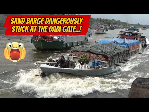 Видео: Баржа с песком опасно застряла у ворот плотины.