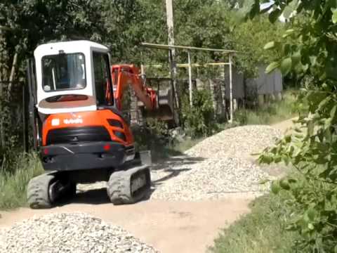 Видео: Мини-экскаватор Kubota U25-3а  ровняет дорогу